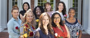 This is a color photo of nine graduates from the American Women's College class of 2019. There are four women in the back row, and five women standing in the front row. They are all looking at the camera and smiling.