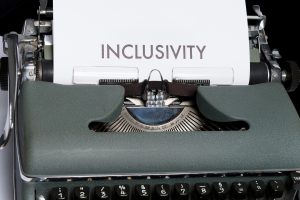 This is an image of a typewriter with a piece of paper inside of it. The word inclusivity in typed on the paper.