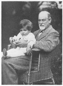 This image shows Sigmund Freud holding little Hans on his lap. Sigmund is seated in a wicker chair outside.