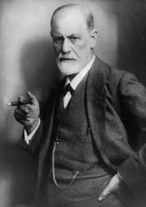 This is a photo of Sigmund Freud standing while smoking a cigar.