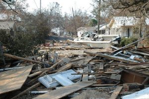 This image shows the damage and destruction to houses caused by hurricane Katrina in Mississippi. The image shows debris piled high with some houses still standing in the background.
