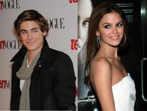 This image shows two celebrities pictured separately in two distinct photos. The photo on the left is a photo of Zac Efron posing in front of a Vogue backdrop. He is wearing a black coat with a gray scarf. The image on the right is a photo of Rachel Bilson posing in front of a large printed advertisement. She is wearing a strapless white dress with large, silver hoop earrings.