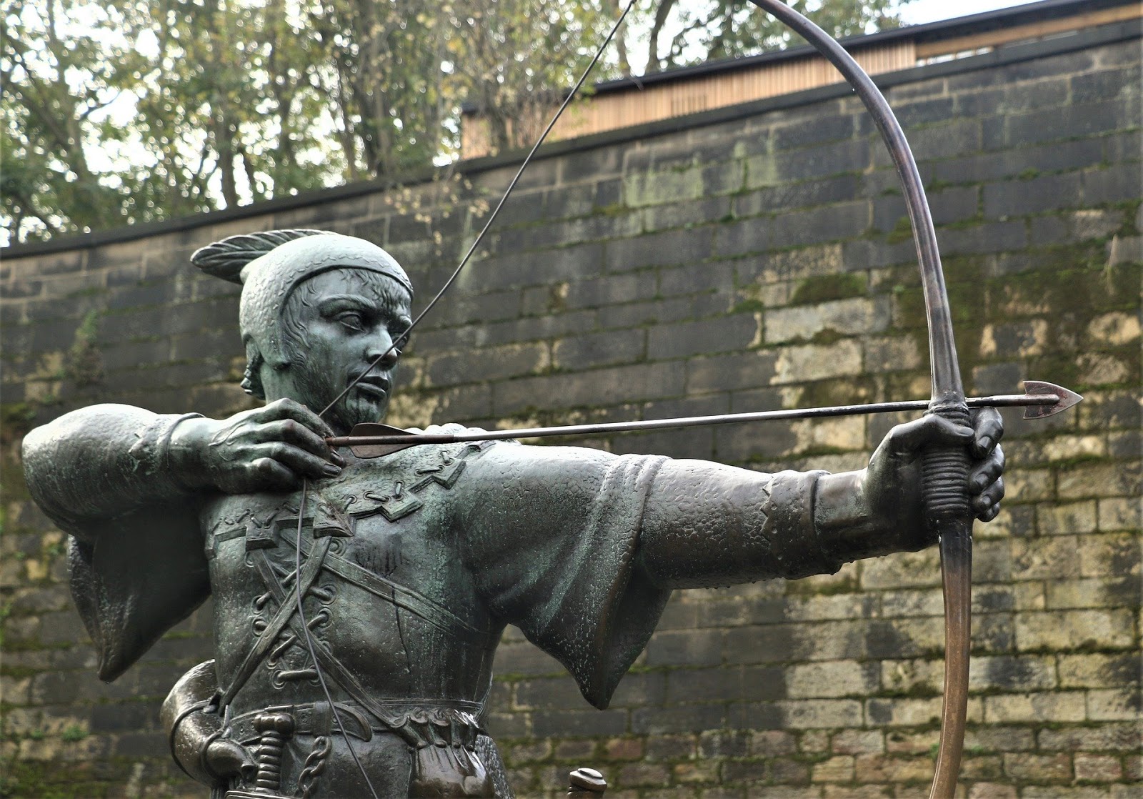 This is a color photo of a sculpted archer. The archer is dressed as Robin Hood, and he is in position to shoot his arrow.