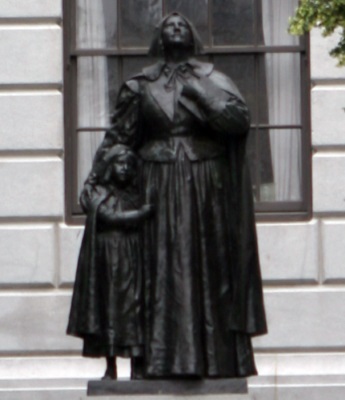 A statue depicting Anne Hutchinson with one of her children.