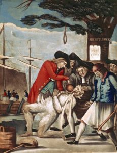 This print depicts the tarring and feathering of a British customs official by the Sons of Liberty in 1774. A man covered in feathers is having tea forcibly poured in his mouth by a mob. In the background, colonists dump tea into the harbour.