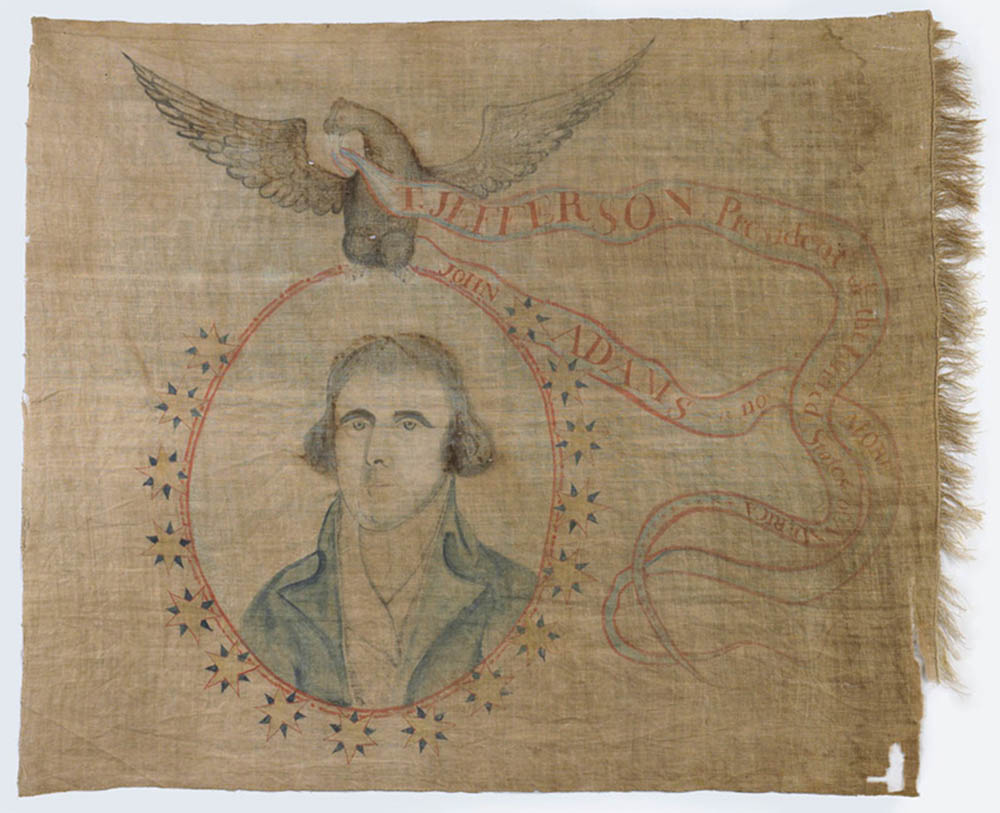This image is a political banner celebrating Jefferson’s victory over Adams in the presidential election of 1800. Jefferson’s portrait is carried by an Eagle. The Eagle also carries the banners of Jefferson and Adams. Jefferson’s banner appears above Adams’ banner indicating that Jefferson was victorious.