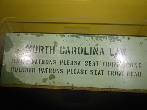 A Jim Crow Law sign for bus segregation in North Carolina reading, ‘White patrons please seat from front - Colored patrons please seat from rear